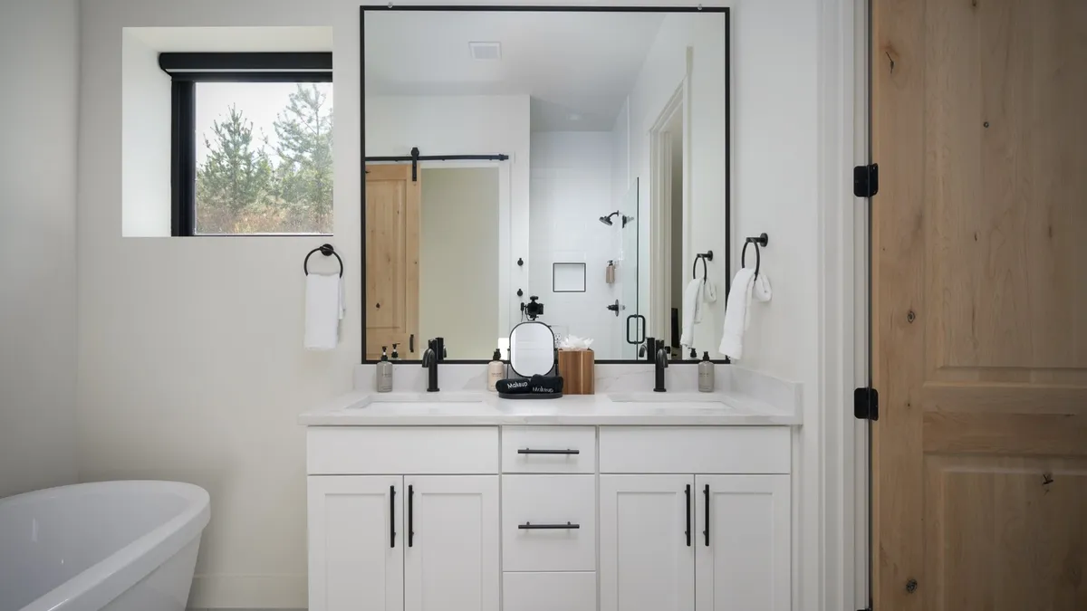 A luxurious ensuite bathroom with a freestanding bathtub, a vanity with a large mirror, and a window offering views of greenery. The space feels rejuvenating and tranquil, ideal for unwinding after adventurous days.
