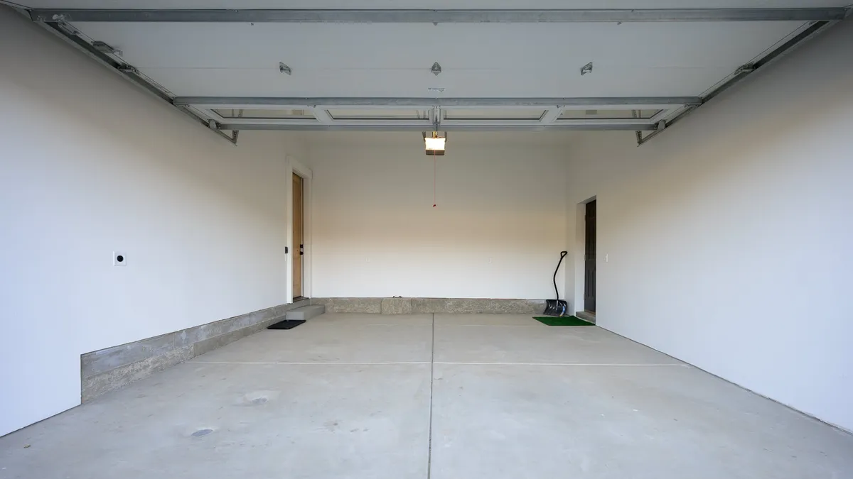 A clean, well-lit garage space with visible garage door, side door, and a spotless floor. The area is organized and functional, ideal for parking vehicles, storing adventure gear, or prepping for outdoor activities.
