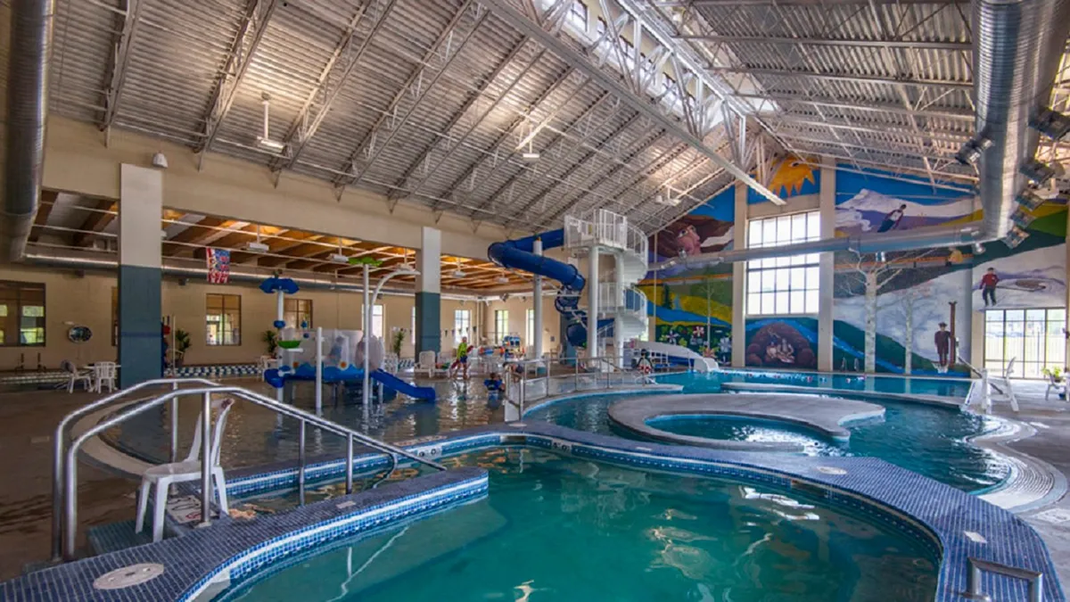 A lively indoor recreation center featuring a colorful swimming pool with water slides, playful murals on the walls, and children laughing and playing in the water. The scene is vibrant and energetic, capturing the essence of family fun and dynamic activities.