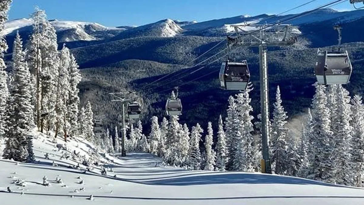 A breathtaking view featuring a gondola lift passing over snow-covered trees, with distant mountains in the background. The scene radiates tranquility and adventure, highlighting the proximity to outdoor resort activities and scenic beauty.