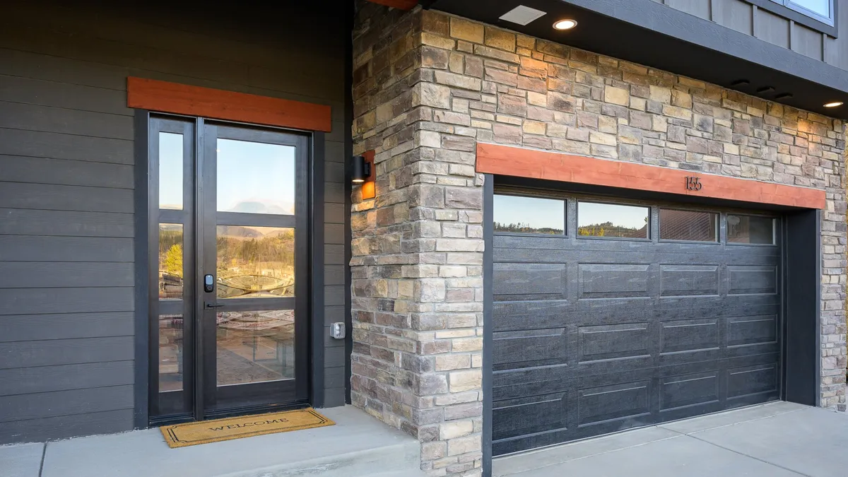 A welcoming exterior shot of the villa's front door and garage, framed by a stone facade. The entryway feels upscale yet inviting, suggesting both the exclusivity and warmth that come with a private home within a resort environment.