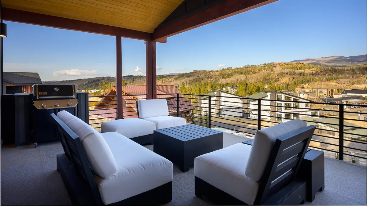 An inviting outdoor seating area with comfortable chairs and a grill, set against a stunning backdrop of mountain views. The space is designed for socializing and relaxation, perfect for enjoying the outdoors with family or friends. The setting hints at both privacy and a connection to nature, reinforcing the idea of a luxury escape with home comforts.